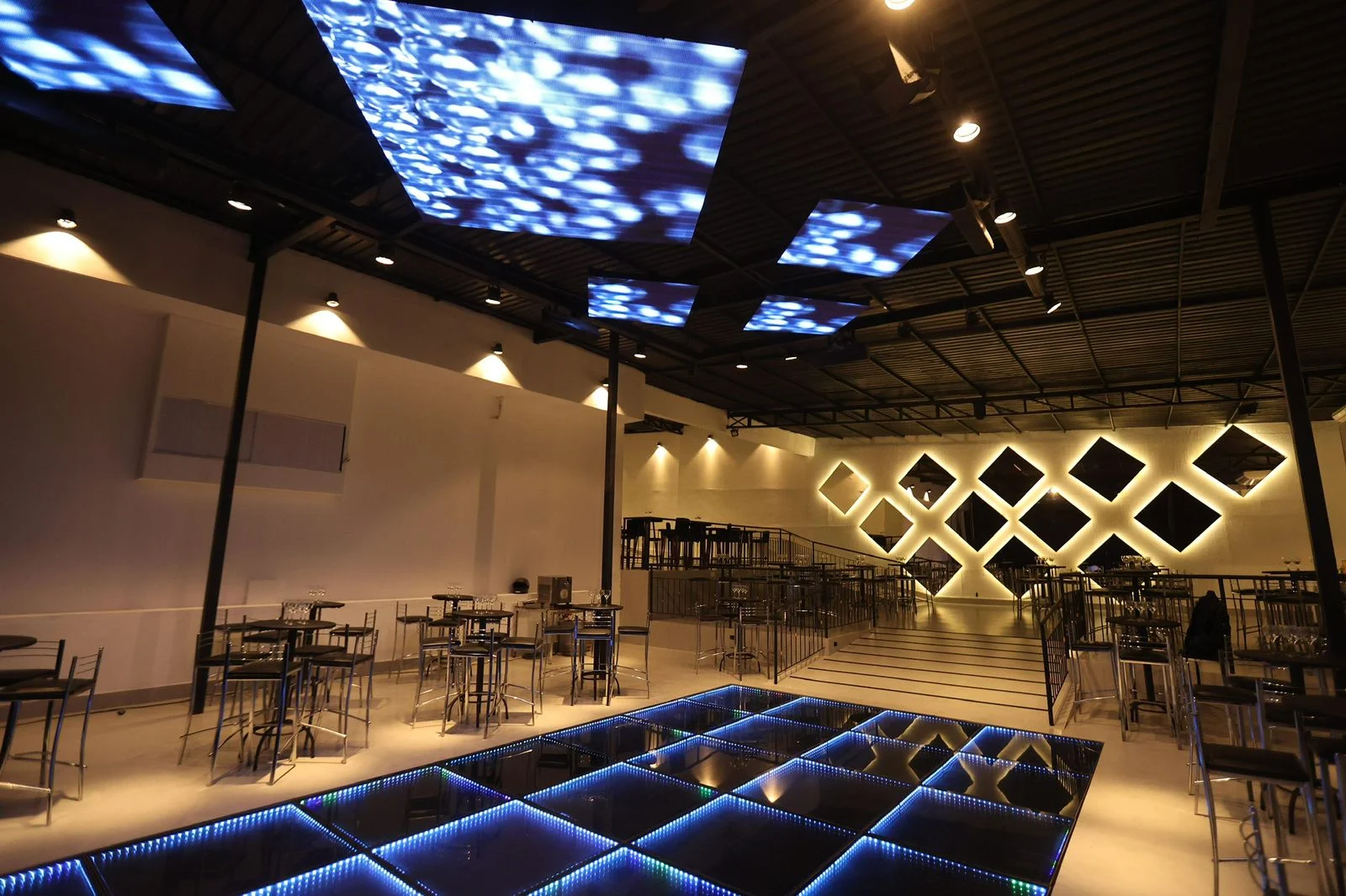 Pista de dança de LED azul e mesas bistrô